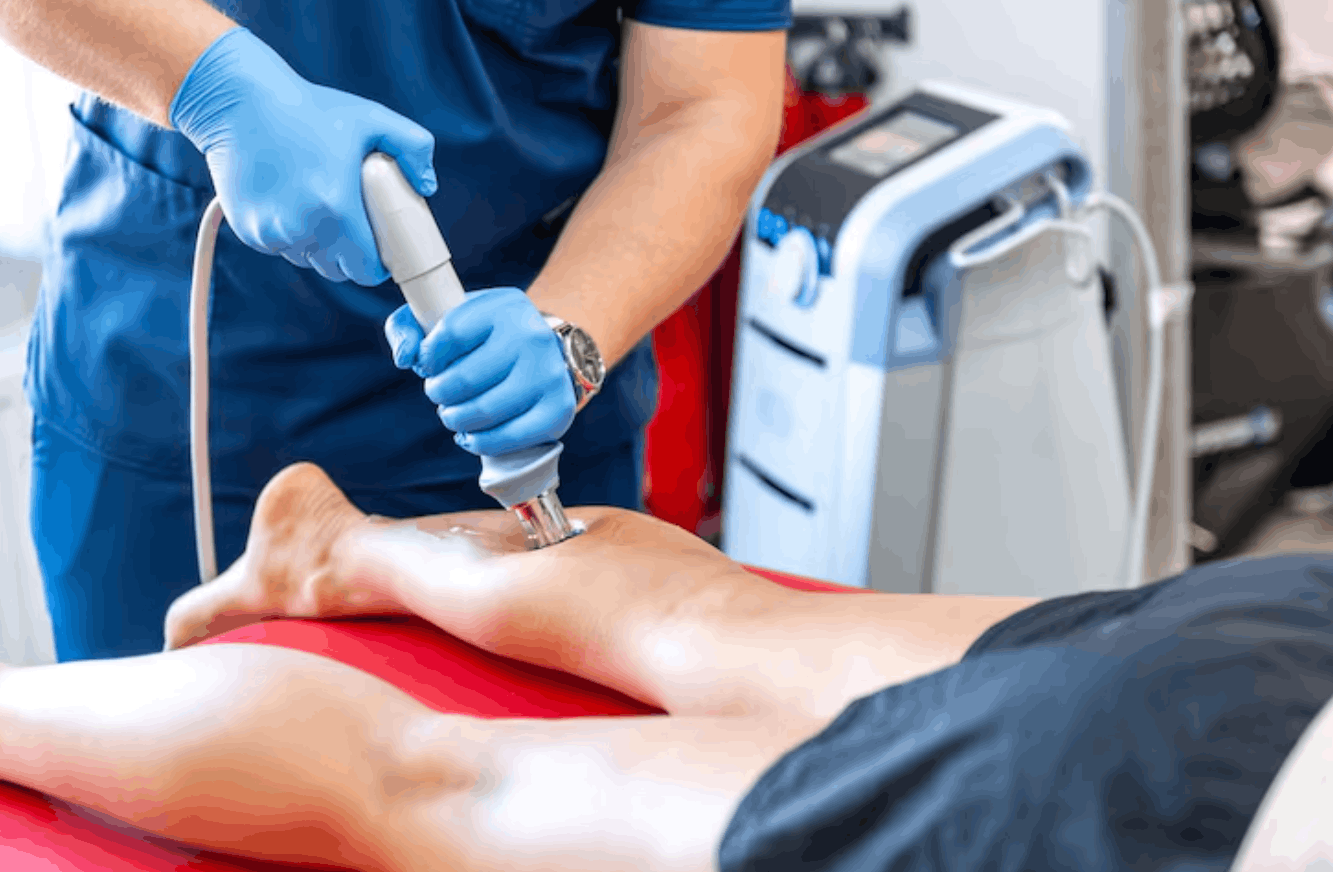 physiotherapist using shockwave therapy on a patient's leg