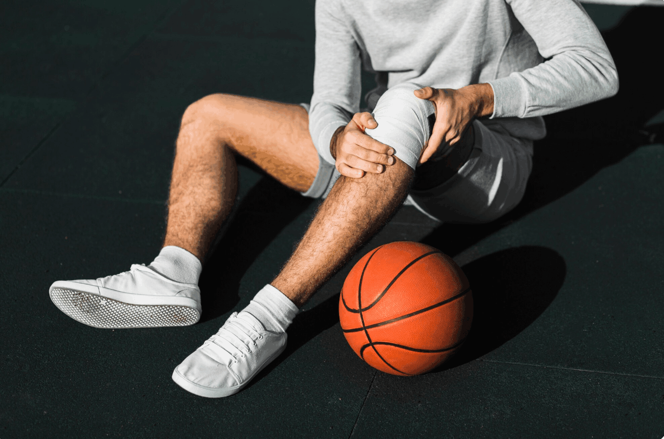 basketball player sitting on the ground holding his knee
