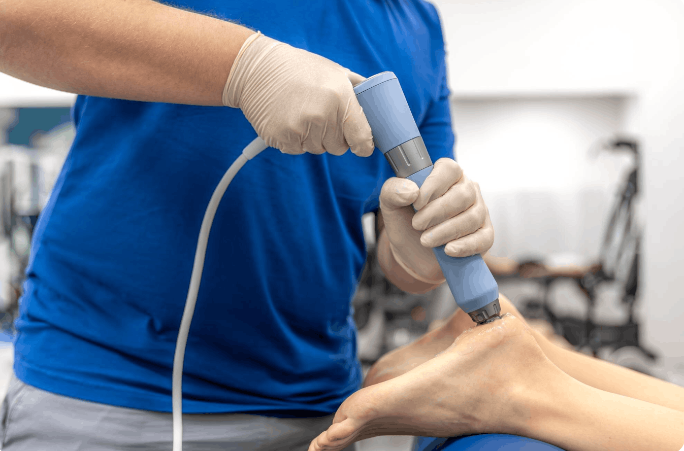 physiotherapist perfoming shockwave therapy on patients foot